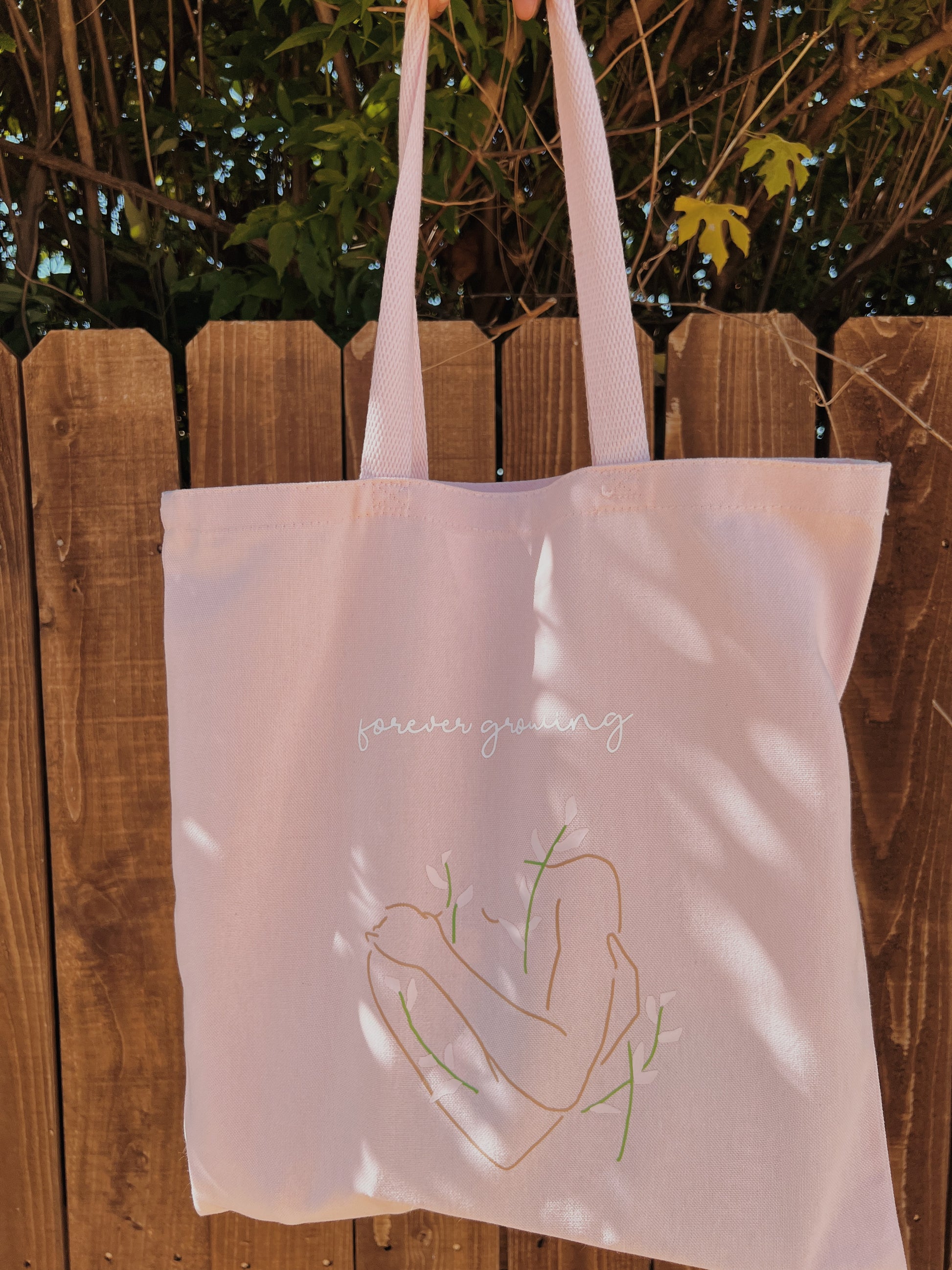 light pink tote in front of brown fence 