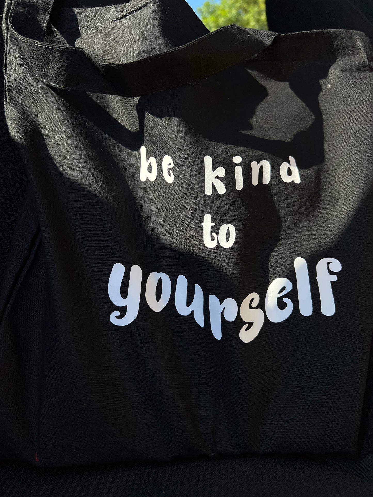 black tote bag with white text laying on car chair